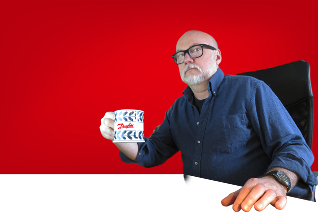 mężczyzna z kubkiem Danfoss na czerwonym tle