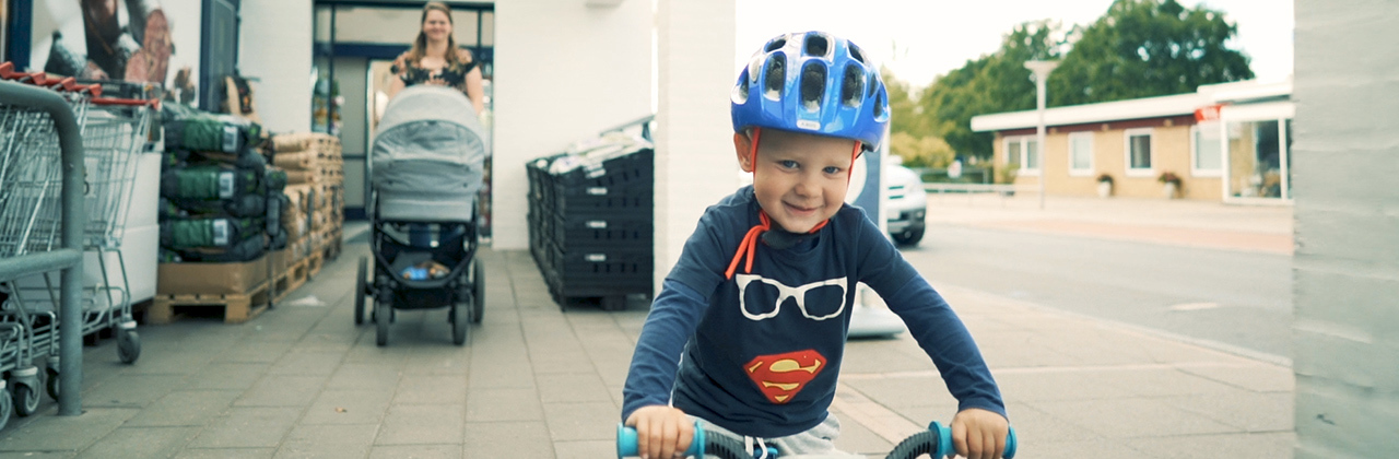Small boy riding his bike in front of supermarket