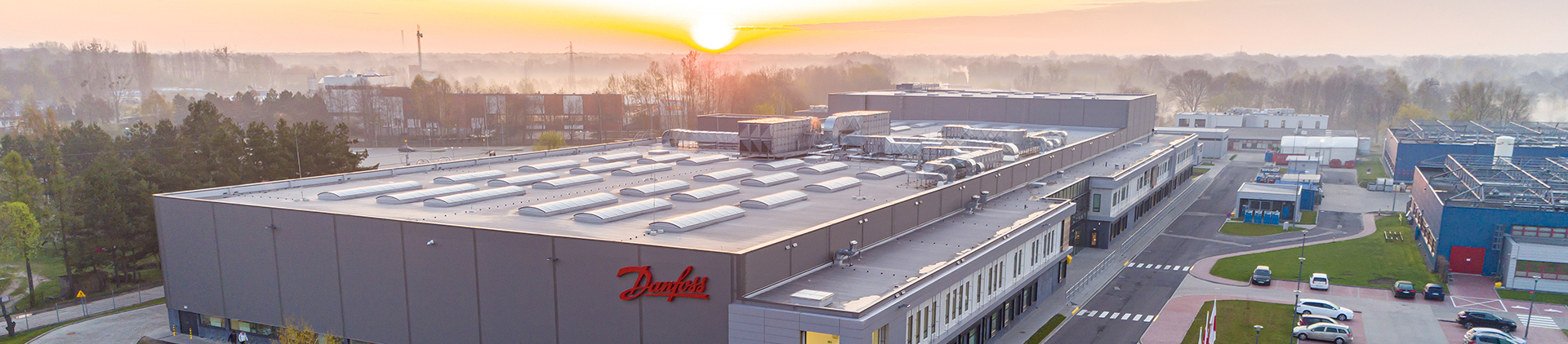 The factory seen from afar, with a sunrise in the back