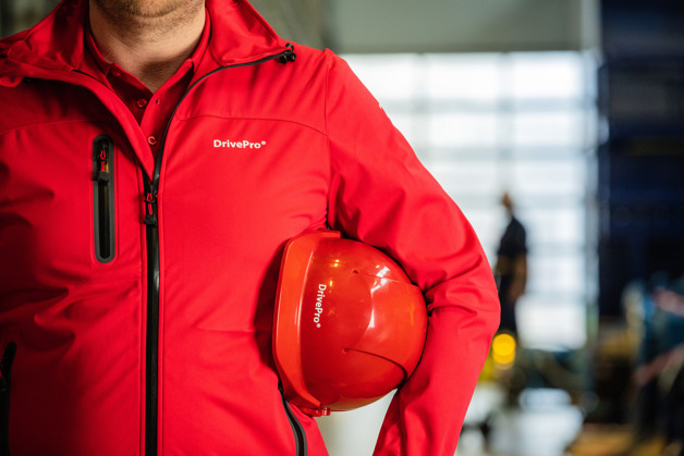 DrivePro man in a red DrivePro jacket with his helmet under his arm